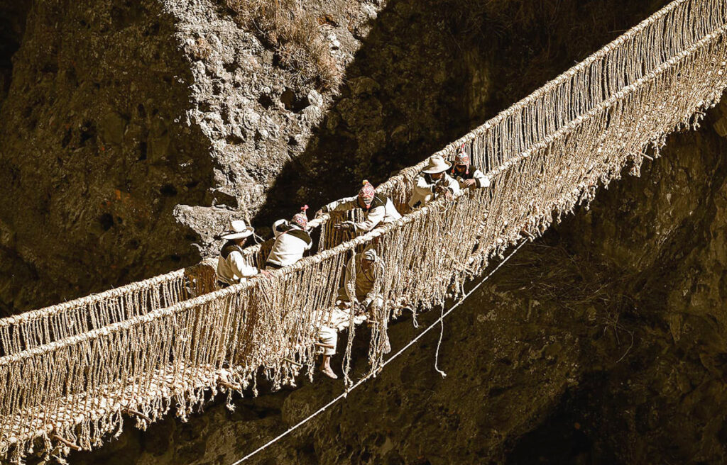 Miembros de cuatro comunidades participan en la reconstrucción del puente Q'eswachaka al atardecer.