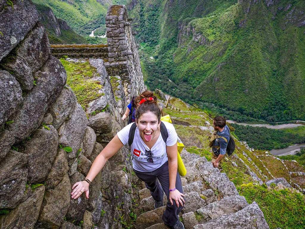 Turistas subiendo por las empinadas escalinatas de piedra del Huayna Picchu, rodeados de naturaleza andina
