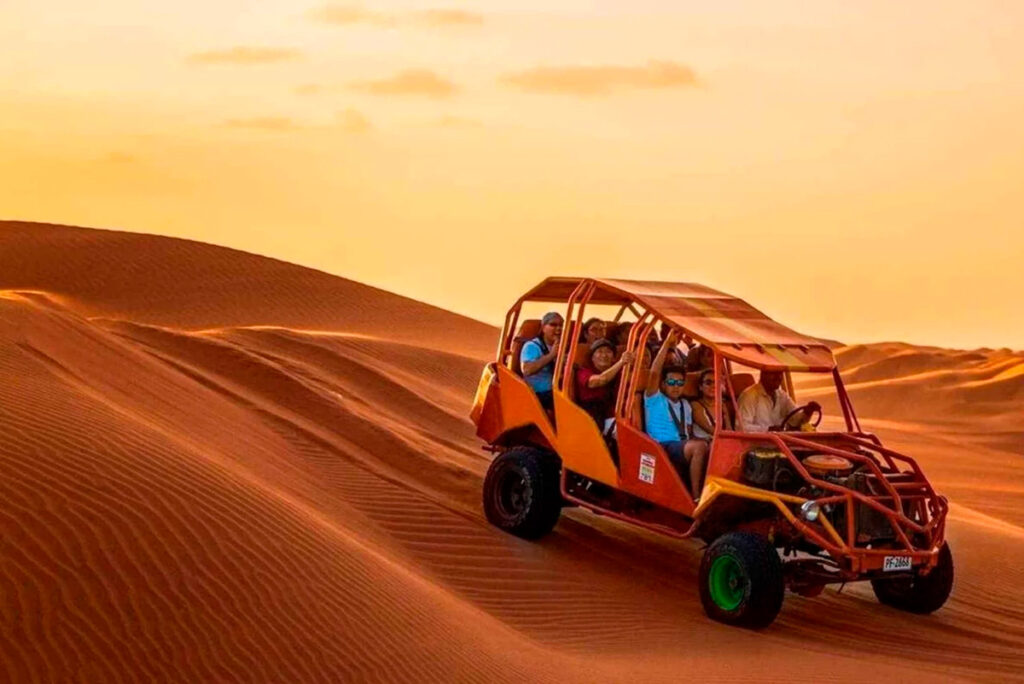 Buggy con turistas recorriendo las dunas de Huacachina al atardecer