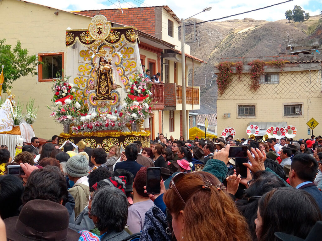 Procesión de la Virgen del Carmen en Huancavelica, con fieles reunidos y andas decoradas en el barrio de Ascensión.