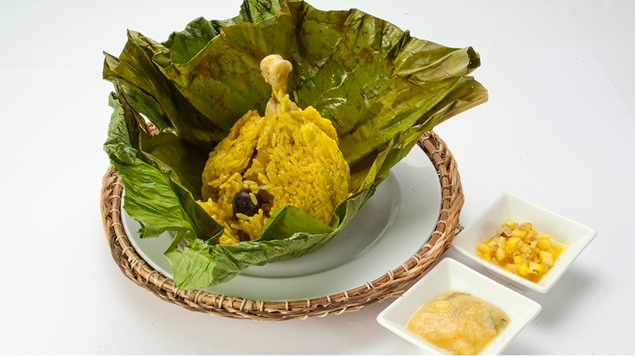 plato de arroz servido en una hoja con una pierna de pollo