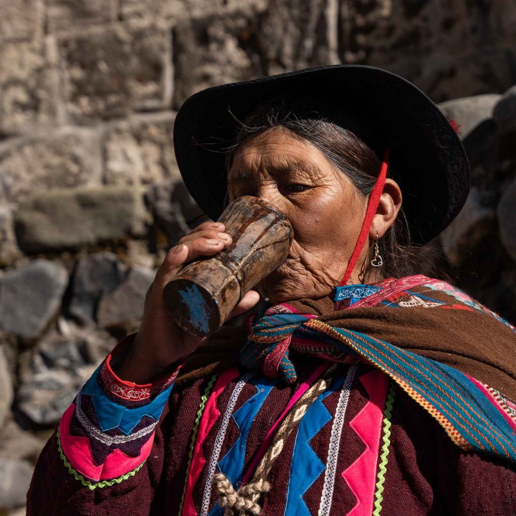 mujer tomando agua de un vaso marron 
