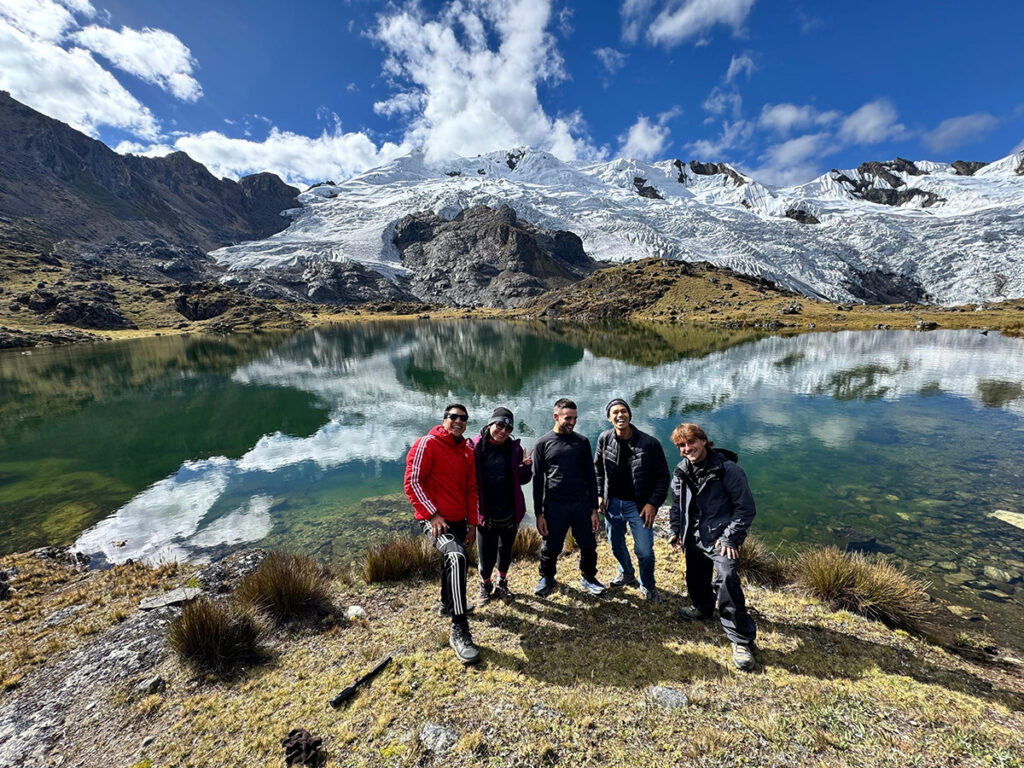 grupo de viajeros frente a la laguna de huaytapallana con los glaciares andinos al fondo