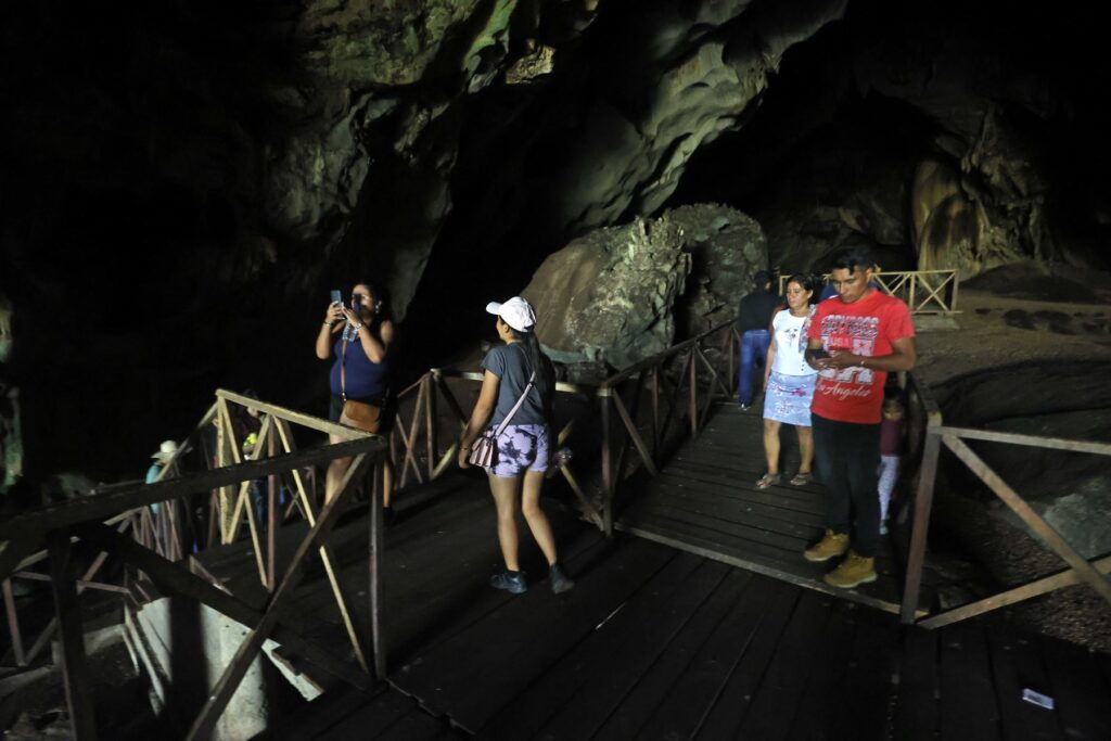 Grupo de visitantes recorriendo la pasarela interior de la Cueva de las Lechuzas con iluminación artificial tenue
