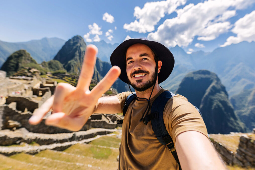 Viajero recorriendo Machu Picchu durante una visita guiada, con vista a las terrazas incas y las montañas que rodean la ciudadela
