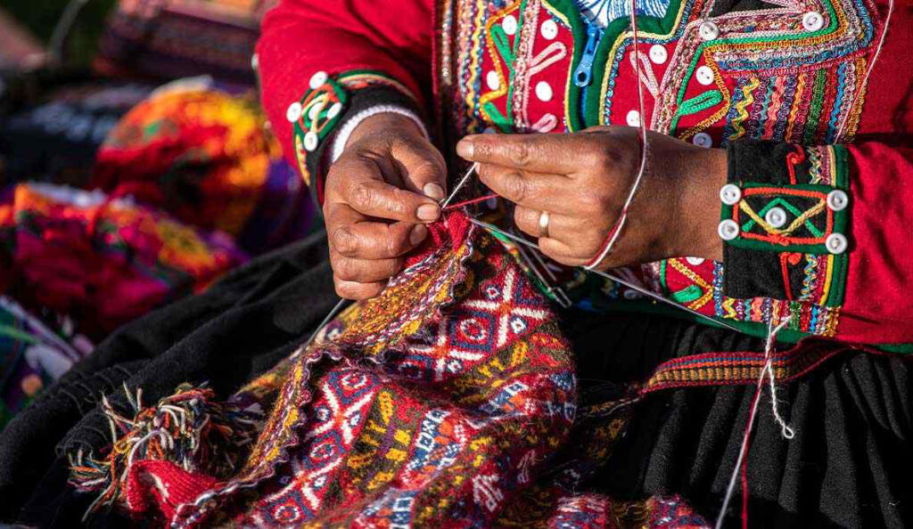 manos de tejedora quechua trabajando tela tradicional en Chinchero, Cusco