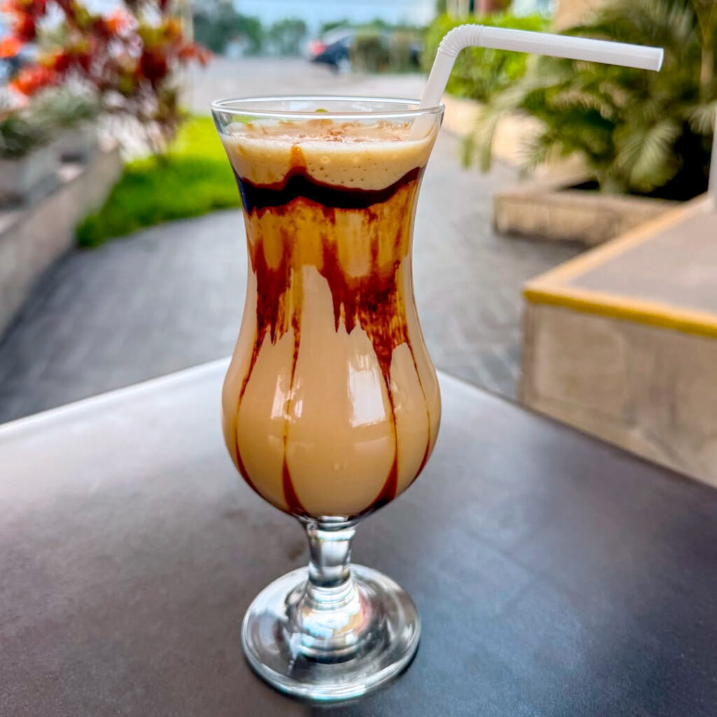 Cóctel de algarrobina servido en vaso largo, bebida típica peruana elaborada con pisco y licor de algarrobo