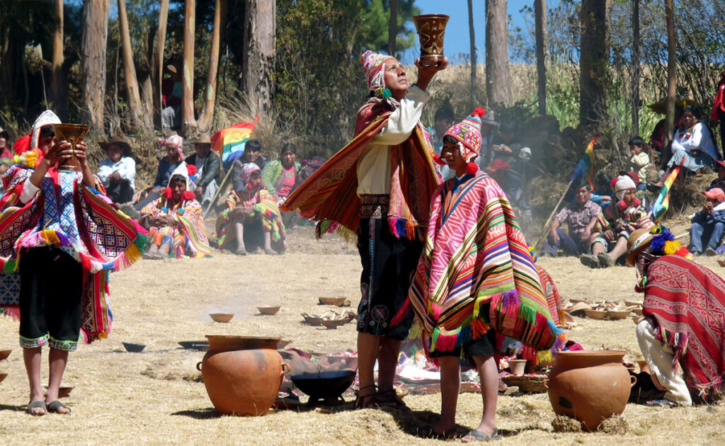 Celebración del Pachamama Raymi en los Andes, con participantes vestidos con trajes tradicionales realizando ofrendas con vasijas de barro y chicha, en un espacio abierto rodeado de eucaliptos.