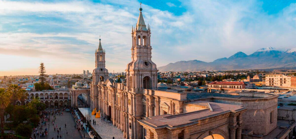 Vista panorámica de la Plaza de Armas de Arequipa con la Catedral y el volcán Misti al fondo, bajo un cielo despejado.