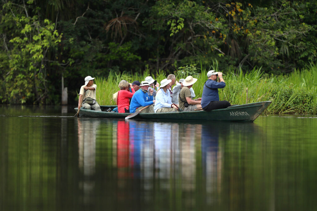 Turistas en bote realizando avistamiento de fauna en el río Tambopata, reserva nacional de Madre de Dios