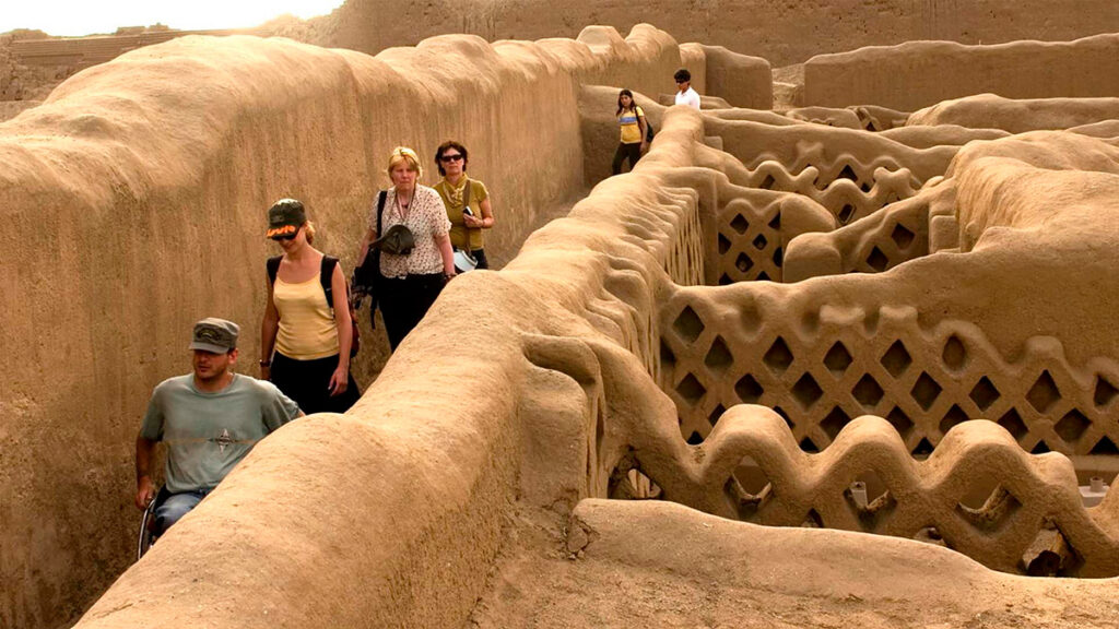 Turistas recorriendo los pasadizos y muros decorados de Chan Chan, la ciudad de adobe más grande del mundo y capital del reino Chimú en Trujillo, Perú