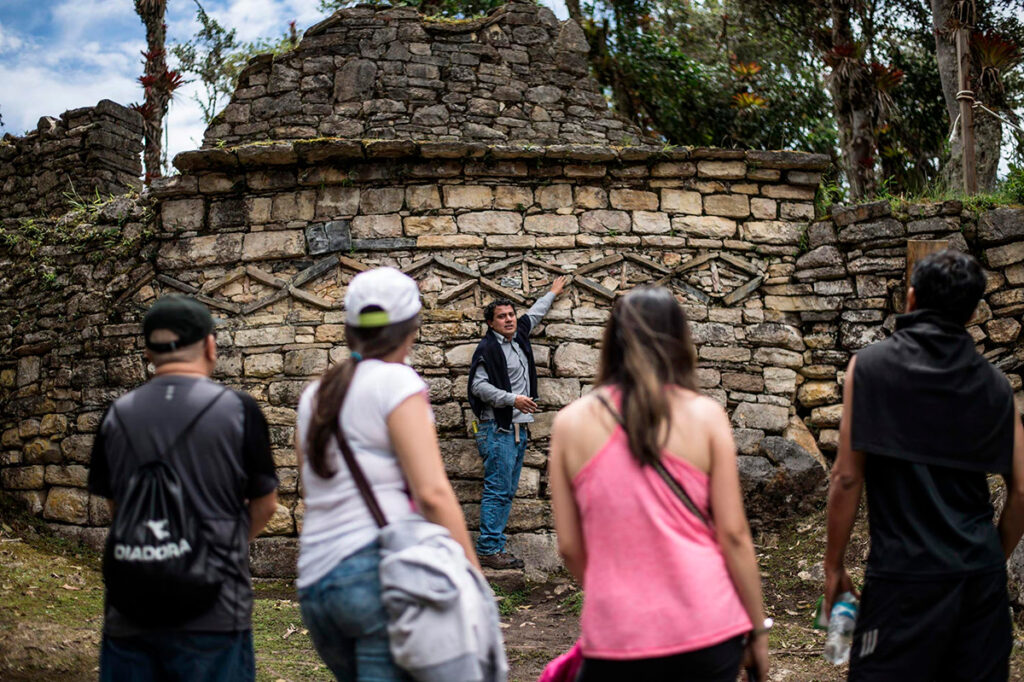 Guía turístico en Kuélap explicando a un grupo de visitantes la historia y arquitectura de la fortaleza preinca de los Chachapooyas en Amazonas, Perú. 
