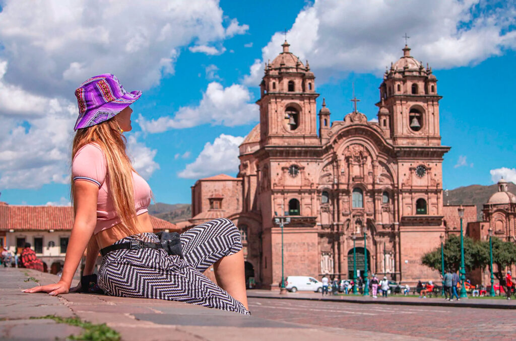 Turista con sombrero tradicional observando la Catedral del Cusco desde la Plaza de Armas, en el corazón del centro histórico