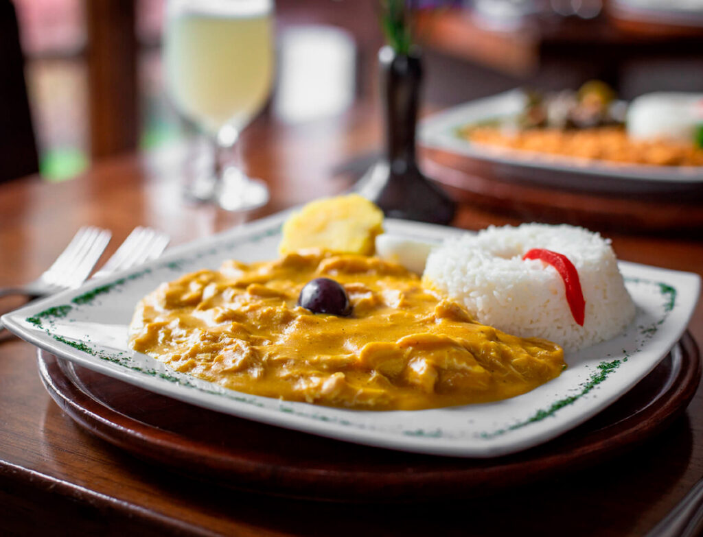 Plato de ají de gallina peruano servido con arroz blanco, papa sancochada y aceituna