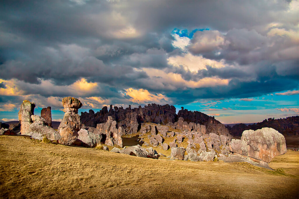 Formaciones rocosas de bosque de piedras de Huayllay iluminadas parcialmente por la luz del atardecer, bajo un cielo nublado
