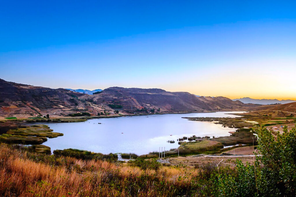 Laguna San Nicolás en Namora, Cajamarca, reflejando el cielo al atardecer antre montañas y campos andinos