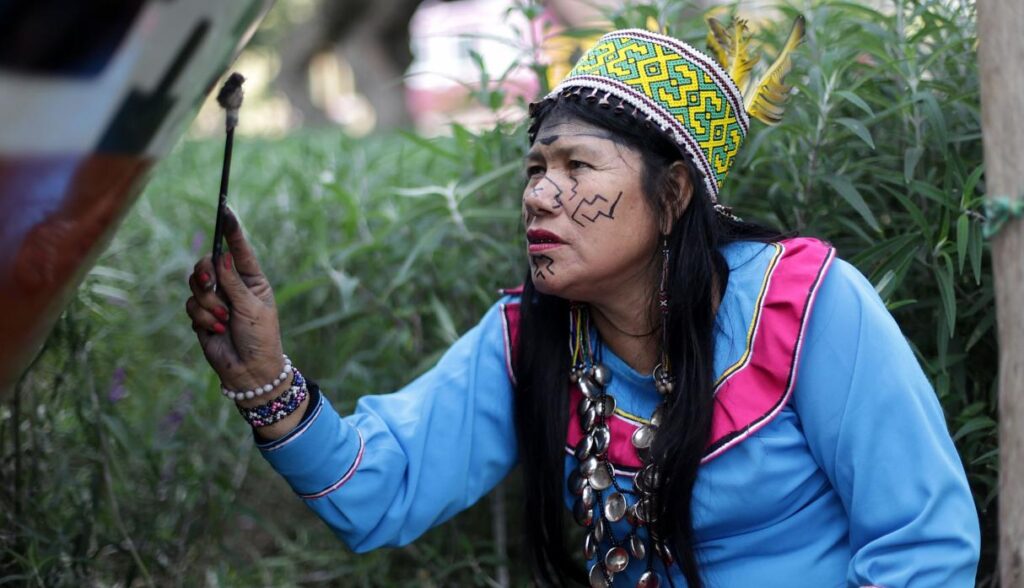 Olinda Silvano pintando arte Kené, vestida del atuendo típico de las mujeres shipibo-konibo