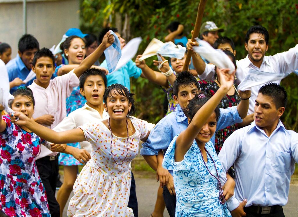 danzantes bailando la pandilla moyobambina, una de las danzas típicas de la selva peruana. Mientras las mujeres visten vestidos floreados, los hombres se caracterizan por sus camisas llanas de colores claros como el celeste o el blanco