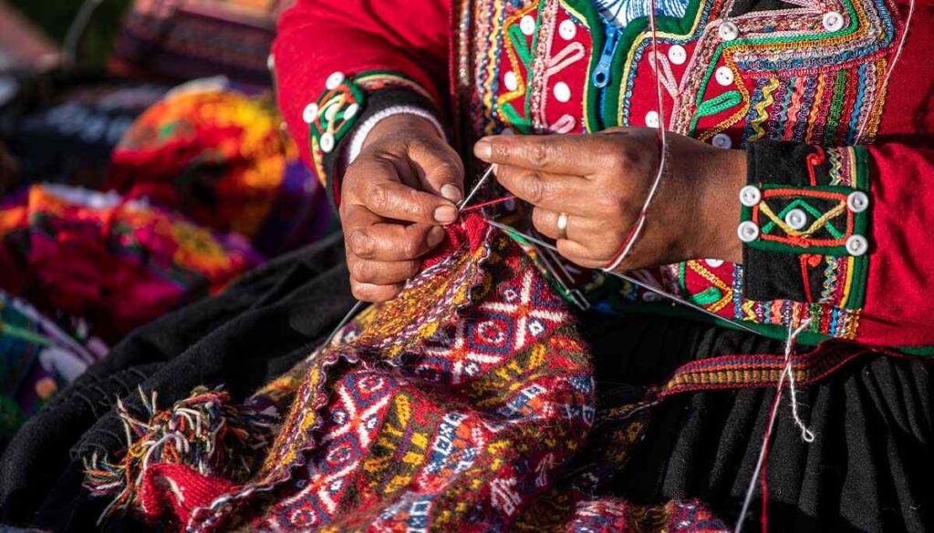 Tejedora de chinchero vestida de ropas típicas de la zona, tejiendo un chullo a mano