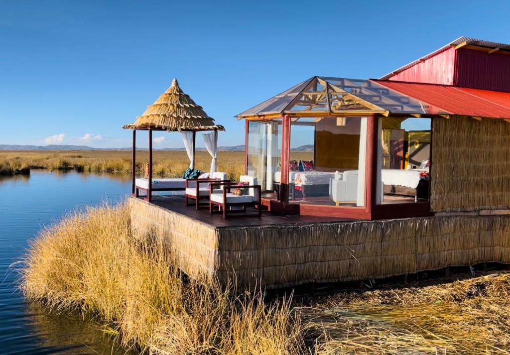 Vista del Eco-lodge Titicaca, construido con totora sobre una isla flotante, con camastros frente al lago y cielo despejado