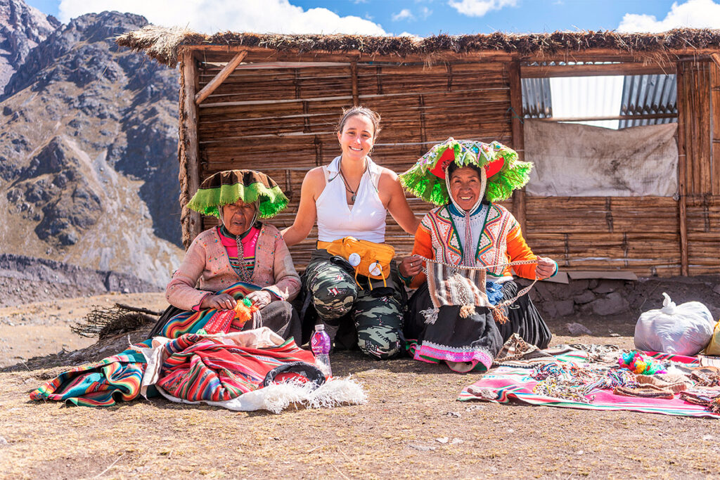 Turista junto a mujeres andinas vestidas tradicionalmente, participando en actividades culturales en los andes peruanos
