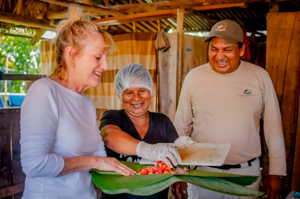 Turista participando de un taller de cocina tradicional con anfitriones locales en una comunidad rural del Perú