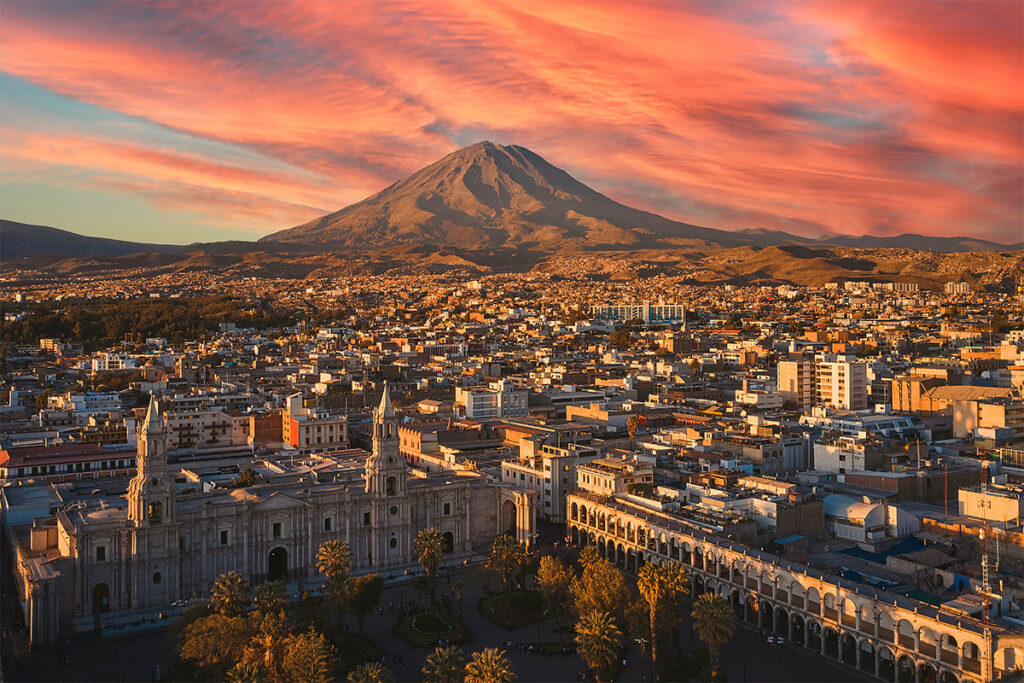 Vista panorámica del volcán misti al atardecer con la ciudad de arequipa en primer plano y un cielo rojizo de fondo