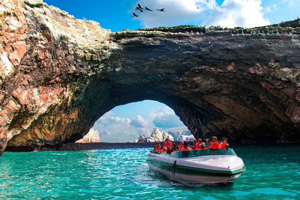 Lancha turística navegando cerca de las formaciones rocosas de las Islas Ballestas, en Paracas