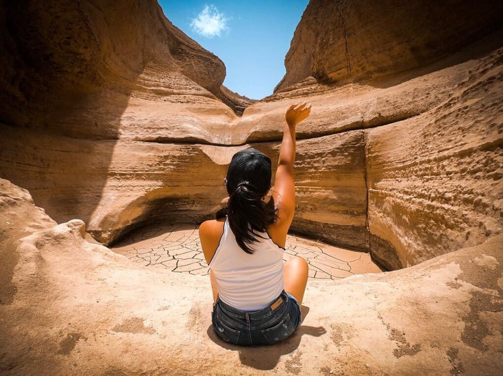 Turista sentada frente a una formación rocosa en el Cañón de los Perdidos, en el desierto de Ica