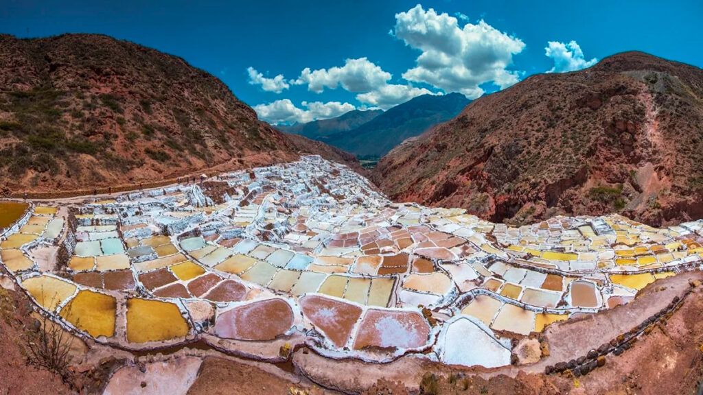 Vista panorámica de las salineras de Maras en Cusco, con pozas escalonadas y montañas rojizas al fondo