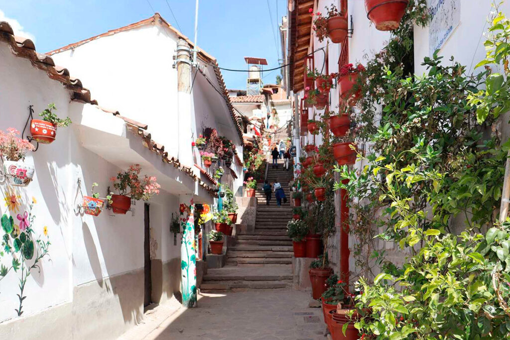 Escalinatas floridas de la calle Siete Borreguitos en Cusco, con fachadas blancas, macetas colgantes y ambiente tranquilo entre San Blas y San Cristóbal