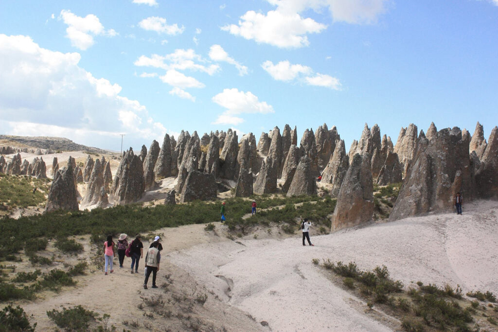 Viajeros recorriendo el Bosque de Piedras de Pampachiri en Apurímac, rodeados de formaciones rocosas cónicas bajo un cielo despejado