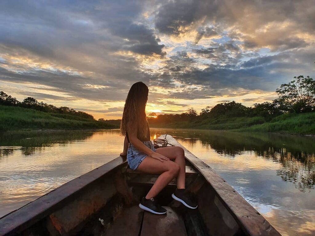 Atardecer sobre el río Amazonas en Iquitos, con viajera navegando entre paisajes amazónicos