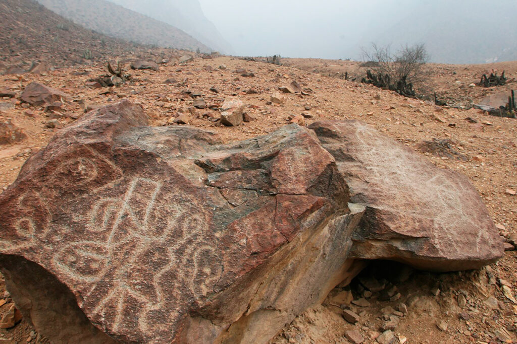 Grabados rupestres en rocas del sitio arqueológico Petroglifos de Checta, en la región andina limeña, rodeados de paisaje árido