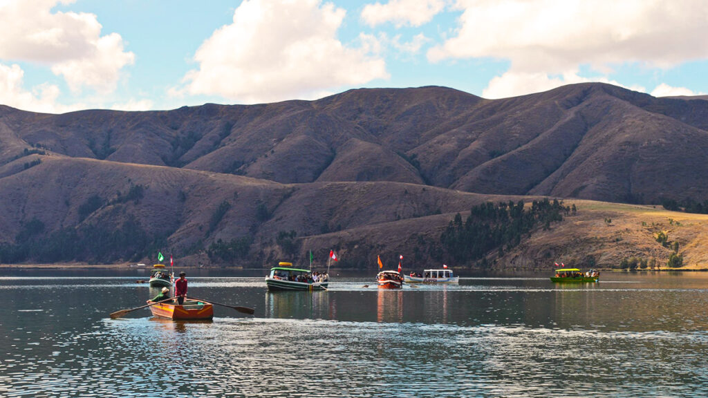 Botes navegando en la Laguna de Paca, rodeada de montañas andinas en el altiplano de Junín, bajo un cielo parcialmente nublado