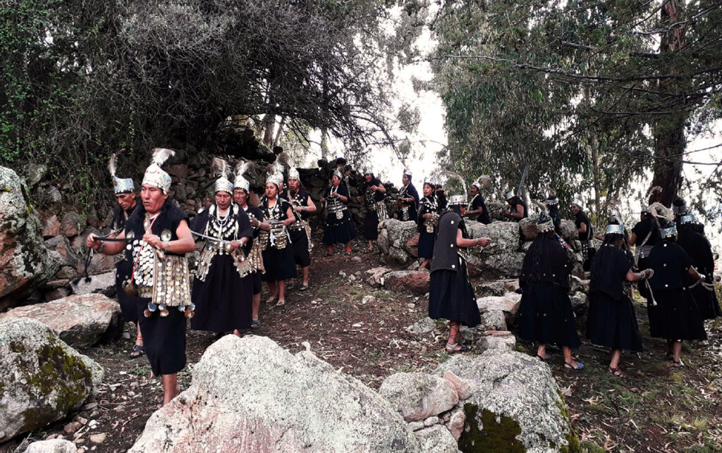 Danzantes de Los Lupakas en formación entre árboles y rocas durante una celebración ritual en Juli, Puno.