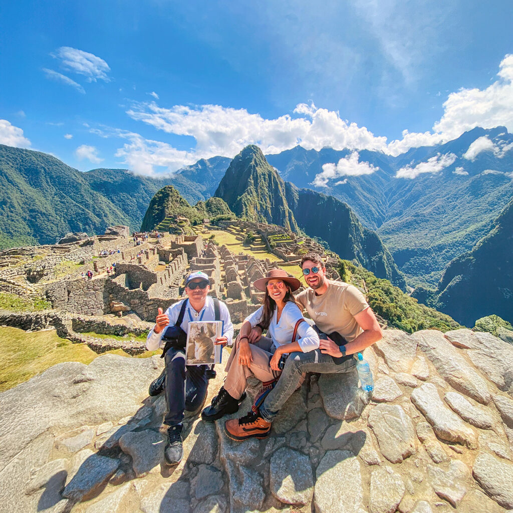 Guía turístico acompañando a dos viajeros en Machu Picchu, explicando la historia del lugar y creando una experiencia cultural enriquecedora en un sitio emblemático del Perú