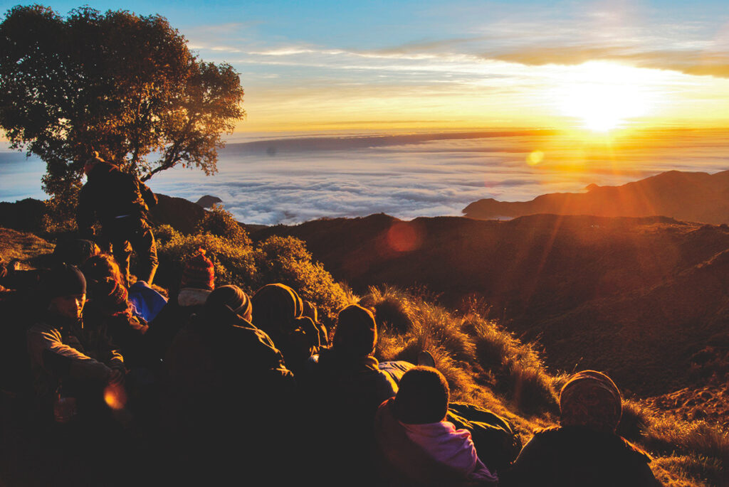 Turistas observando el amanecer desde el Mirador de Tres Cruces en Paucartambo, Cusco, con vista a la selva y cielo despejado