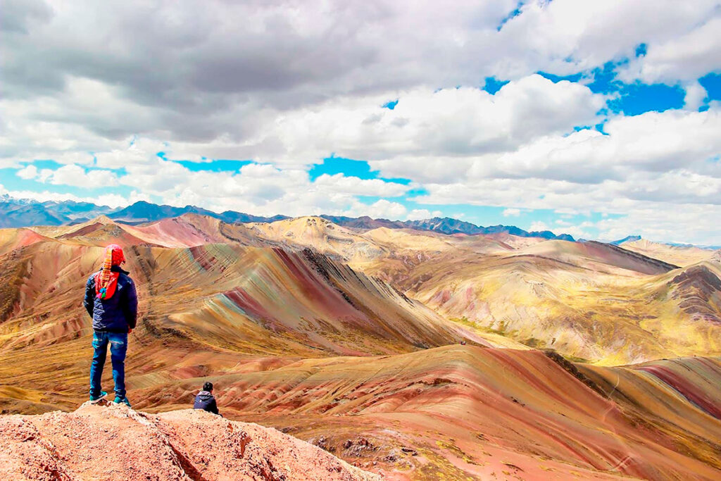 Viajero contemplando las montañas de colores de Palcoyo en un día despejado