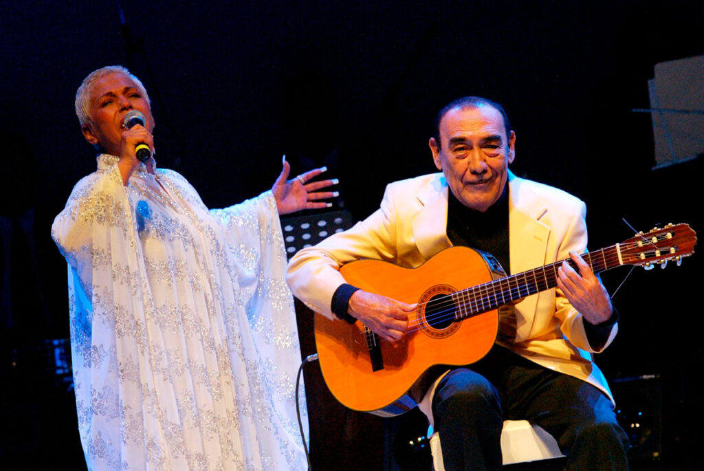 La cantante criolla y el guitarrista Óscar Avilés interpretando música en vivo sobre un escenario iluminado