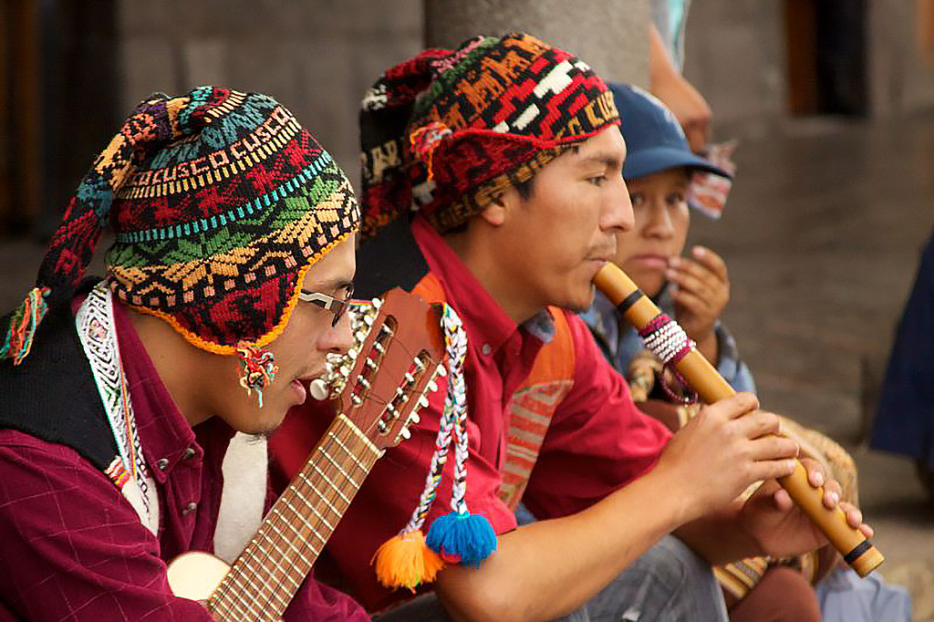 Músicos andinos tocando zampoña y charango con vestimenta tradicional de la sierra peruana