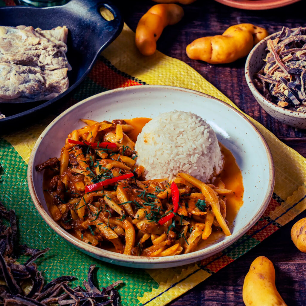 Plato de olluquito con charqui acompañado de arroz, rodeado de ingredientes andinos tradicionales