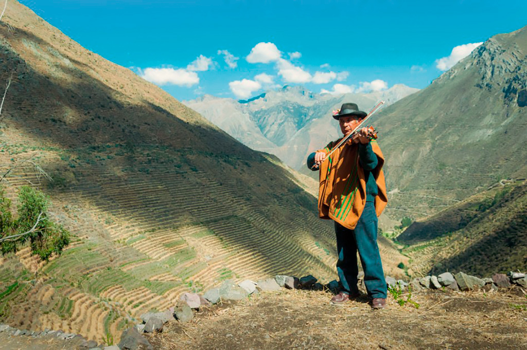 Comuneros de Laraos con charango sobre los andenes agrícolas del valle de Yauyos, rodeado de montañas andinas