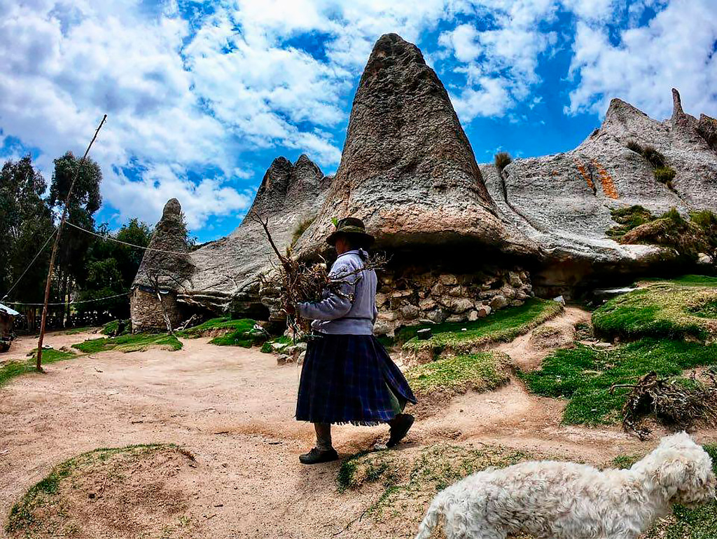 Mujer andina caminando junto a formaciones pétreas en Pampachiri, reflejo de la vida comunal y tradición oral del lugar