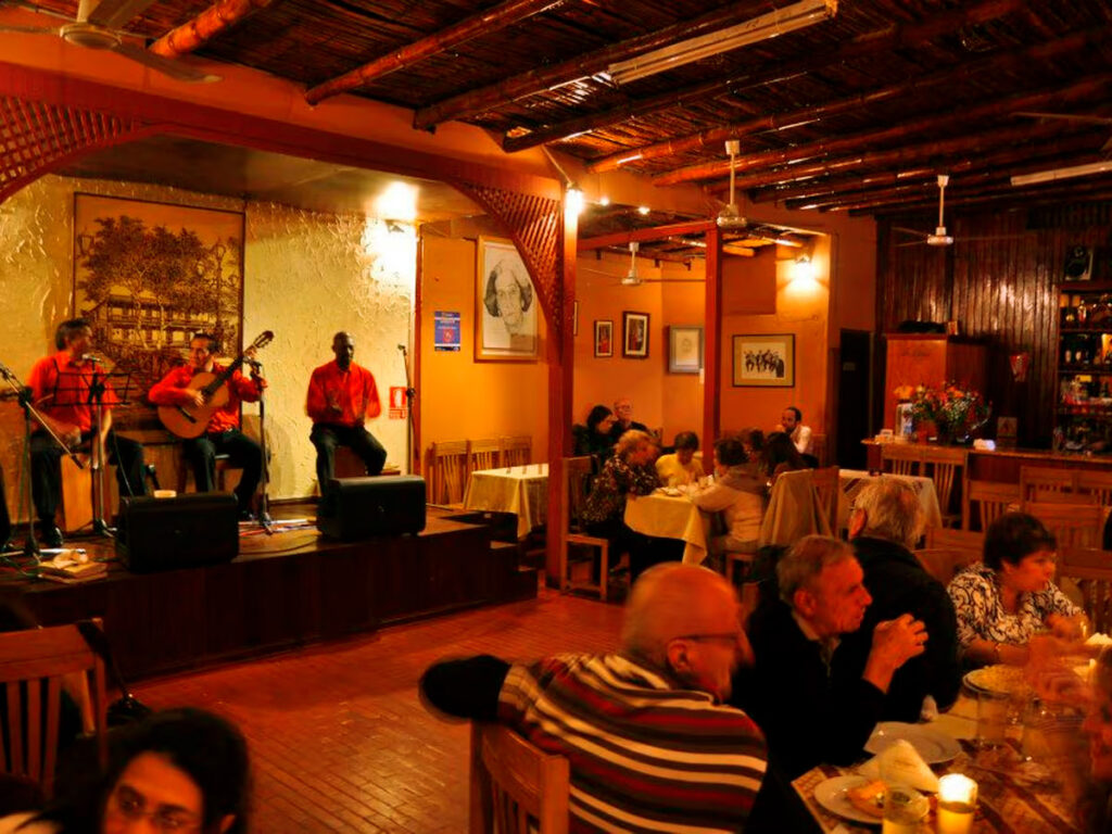 Peña criolla en Lima con músicos en vivo y comensales disfrutando música, comida y baile