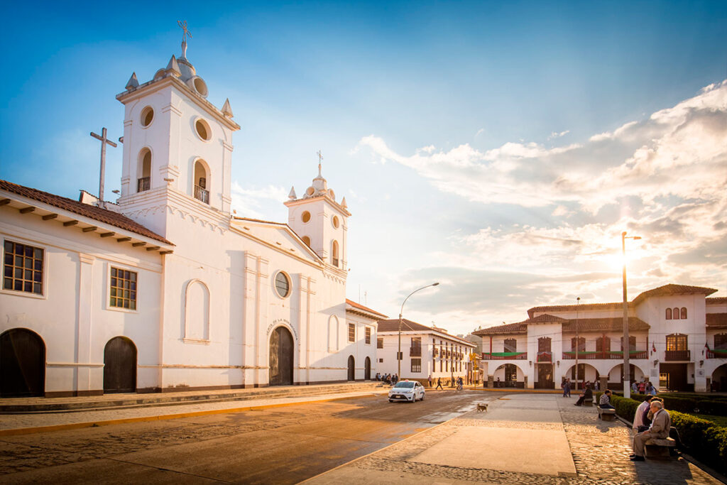 Plaza de Armas de Chachapoyas iluminada por luz dorada con iglesia blanca y fachadas coloniales al atardecer