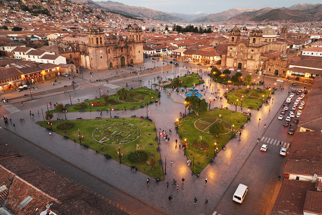 Vista aérea al atardecer de la plaza de armas del Cusco con la Catedral iluminada y calles empedradas 