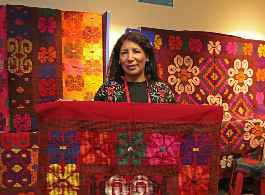 Artesana de San Pedro de Cajas mostrando tapices coloridos con motivos andinos 