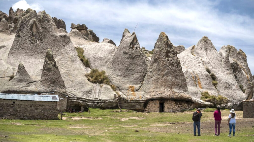 Casas construidas bajo formaciones rocosas en Pampachiri, con visitantes recorriendo la zona como parte del turismo rural