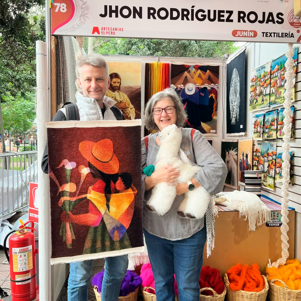 Pareja de turistas mostrando artesanías textiles de San Pedro de Cajas, compradas de una feria de textiles peruanos